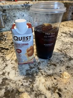 a bottle of quest iced caramel next to a plastic cup on a granite countertop