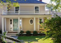 a house with a blue roof and white trim on the front door is surrounded by greenery