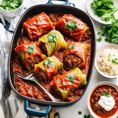 stuffed cabbages with meat and vegetables in a blue casserole dish on a white table