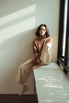 a woman is sitting on a window sill