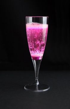 a glass filled with pink liquid sitting on top of a table