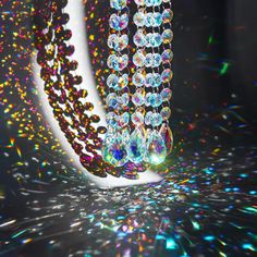 an array of colorful beads and chains on a black surface with multicolored lights