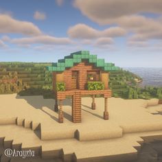 a small wooden structure sitting on top of a sandy beach next to the ocean in minecraft