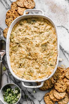 a casserole dish filled with broccoli and cheese next to crackers