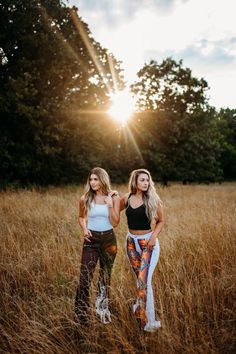 two women standing in tall grass with the sun behind them