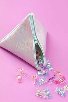 a white zippered pouch filled with lots of small plastic clips on top of a pink surface