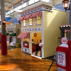 a toy house is on display in a building with wooden floors and red and white awnings