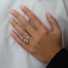 a woman's hand with two rings on top of her finger, resting against a white pillow