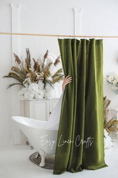 a white bath tub sitting next to a green curtain