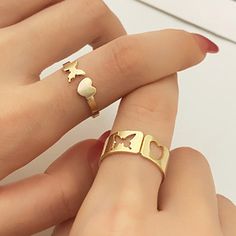 two gold rings with hearts and stars on each one, sitting next to each other