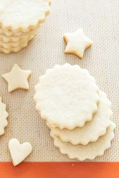 some cookies are sitting on a table with white icing and star shaped cookies next to them