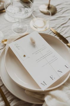 a table setting with white plates and gold place settings, napkins and utensils