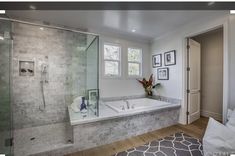 a bathroom with a tub, shower and rug in the middle of the flooring