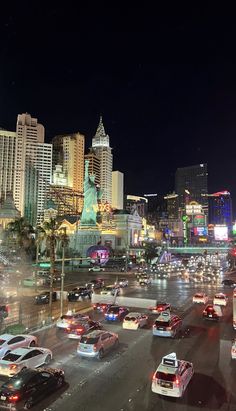 a busy city street filled with lots of traffic and tall buildings in the background at night