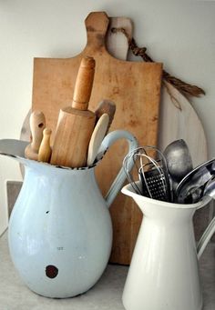 a white pitcher filled with kitchen utensils on top of a counter next to a cutting board