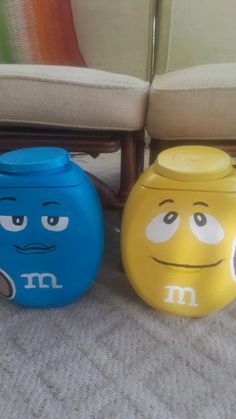 three different colored plastic containers sitting next to each other on the floor in front of a couch