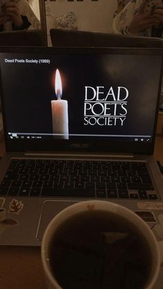 a laptop computer sitting on top of a wooden table next to a cup of coffee