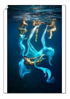 three people are swimming in the water with long blue fabric on their backs and feet