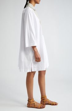 Volume rules the day in this crisp cotton shirtdress designed with strong shoulders and clusters of dense gathering front and back. A contrast bib and yoke in a neutral hue stand out against the optic-white poplin. Hidden-button half-placket Spread collar Bracelet-length sleeves Side-seam pockets Side slits 100% cotton with 95% cotton, 3% silk, 2% elastane contrast Dry clean or machine wash, line dry Made in Italy Designer Clothing Spring Daywear Shift Shirt Dress, Shift Shirt Dress For Spring Daywear, Spring Shift Shirt Dress For Daywear, Elegant Poplin Daywear Dresses, Elegant Poplin Dresses For Daywear, Cotton Shift Shirt Dress With Collar, Cotton Shift Collared Shirt Dress, Cotton Shift Shirt Dress Knee-length, Knee-length Cotton Shirt Dress