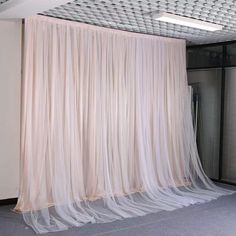 an empty room with sheer curtains on the wall and carpeted flooring in front of it