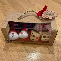 three little stuffed animals in a box on the floor with red and white striped socks