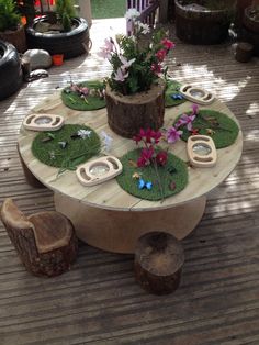 a wooden table with flowers and plants on it in the middle of a patio area