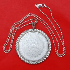 "A gorgeous sterling silver necklace, set with an authentic Mexico 1 oz Silver Round BU Uncirculated Coin - Aztec Calendar. Obverse: Depicts the famous Aztec Calendar stone. The design is in a circular shape resembling a sun, with rays emanating outward. In the center is the face of the Aztec solar deity, Tonatiuh, which gives the monolith its alternate name the Sun Stone. Reverse: depicts the striking left portrait of Cuauhtemoc, the last Aztec Emperor of Tenochtitlan. The name Cuauhtemoc means Etched White Gold Round Pendant Necklace, White Gold Etched Round Pendant Necklace, Etched Round Necklace For Anniversary, Etched Necklaces For Anniversary, Etched Necklace For Anniversary, Traditional Engraved Round Coin Necklace, Etched Sterling Silver Round Necklace, Engraved Sterling Silver Round Medallion Necklace, Engraved Round Sterling Silver Medallion Necklace