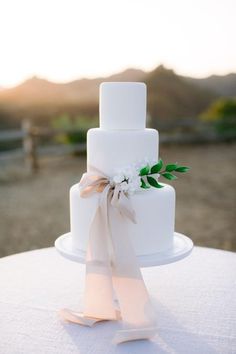 a white wedding cake sitting on top of a table next to an instagram page