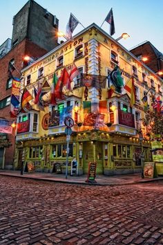 the building has many flags on it's side and lights shine brightly in the windows