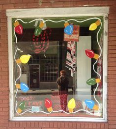 a person standing in front of a store window with balloons on the windowsills