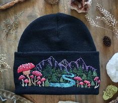 a beanie hat with an image of a river running through trees and mushrooms on it