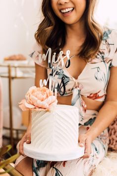 a woman holding a cake with the words miss and mr on it in front of her