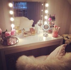 a vanity with lots of lights on top of it next to a mirror and teddy bear