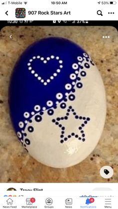 a blue and white painted rock with a heart on it's side, sitting on a marble surface