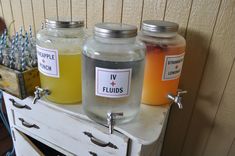 three jars filled with liquid sitting on top of a dresser