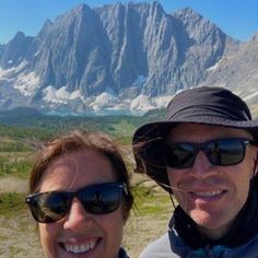 a man and woman taking a selfie in front of a mountain range with their sunglasses on