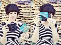 a woman taking a selfie in front of wooden pallets holding up her camera