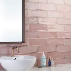 a white sink sitting under a bathroom mirror next to a wall mounted faucet