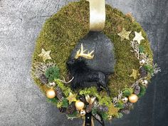 a christmas wreath with deer antlers, pine cones and balls