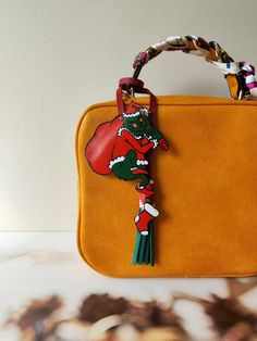 an orange purse with a tassel hanging from it's handle and decorated with a red pomegranate