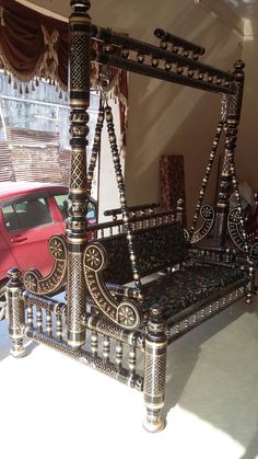 a metal bed frame sitting in the middle of a room next to a red car