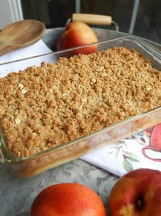 an apple crumb topping in a glass dish next to apples