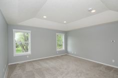 an empty room with two windows and carpet