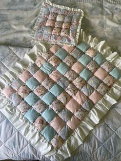 a quilted blanket and pillow on top of a bed with blue and pink pillows