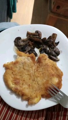 a white plate topped with meat and mushrooms on top of a red striped table cloth