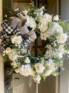 a wreath with white flowers and greenery on the front door