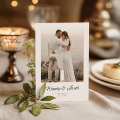 a wedding photo on a table next to a candle and some plates with desserts