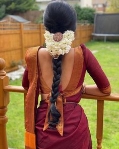 the back of a woman's head with flowers in her hair, sitting on a wooden bench