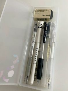 three pens and two erasers in a plastic container