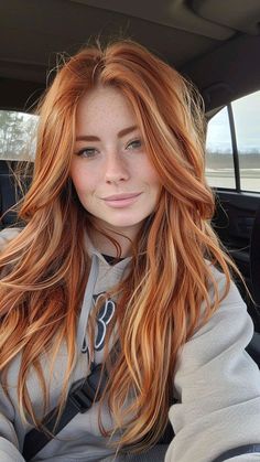 a woman with red hair sitting in the back seat of a car looking at the camera